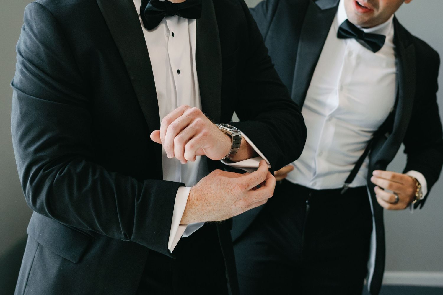 A group of people in formal black tuxedos and bow ties stand together in a row.