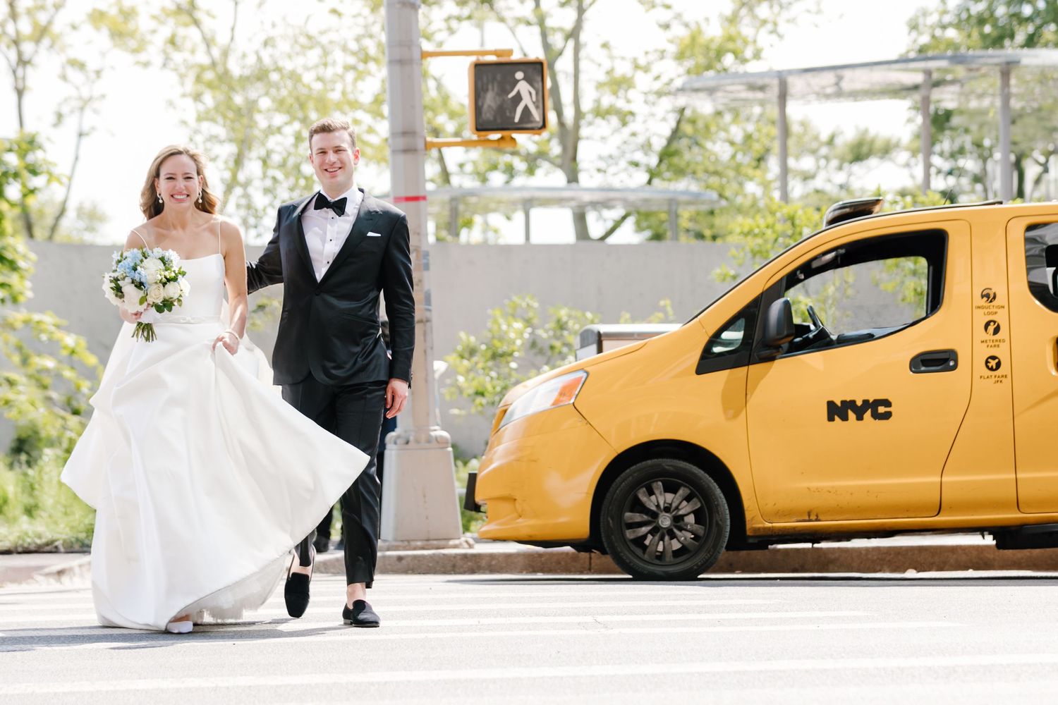 A bride and groom walk past a yellow NYC taxi cab in an urban wedding photo.