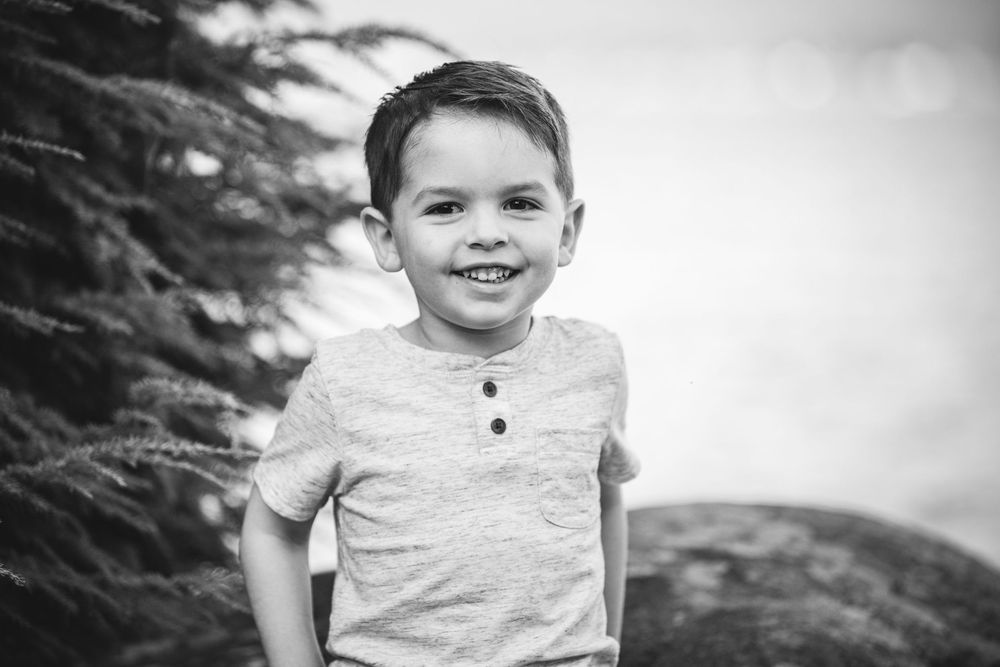A series of black and white portraits of a child in casual clothing against a natural outdoor background.