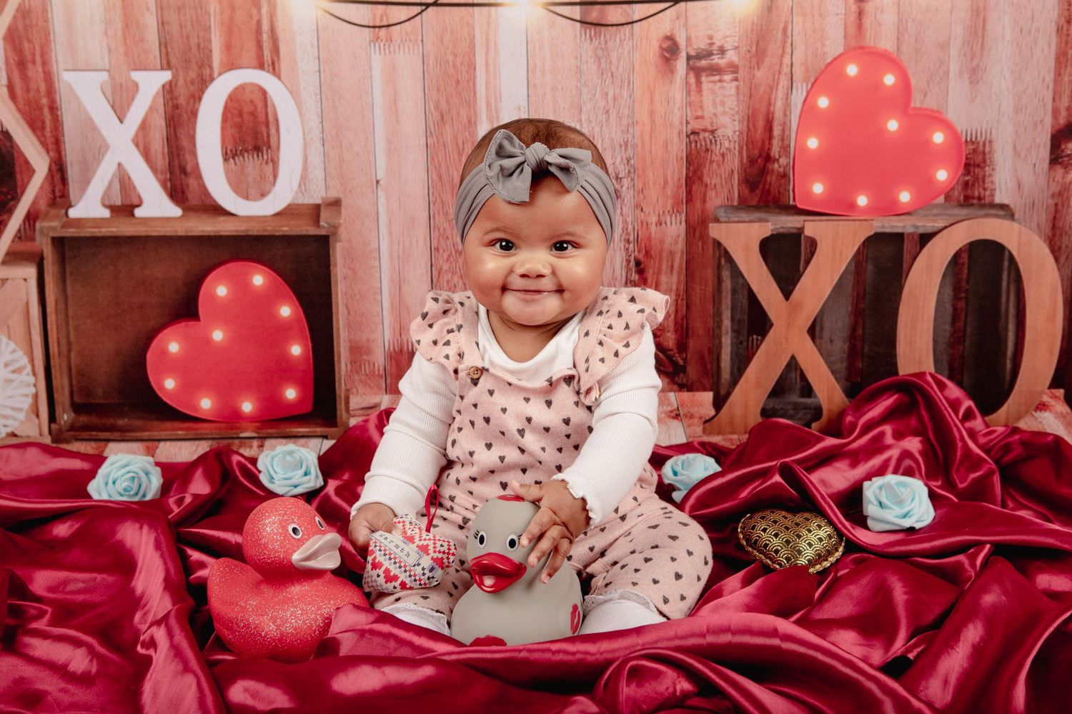 Red and pink Valentine's Day themed photoshoot setup with heart decorations and rustic wooden backdrop.