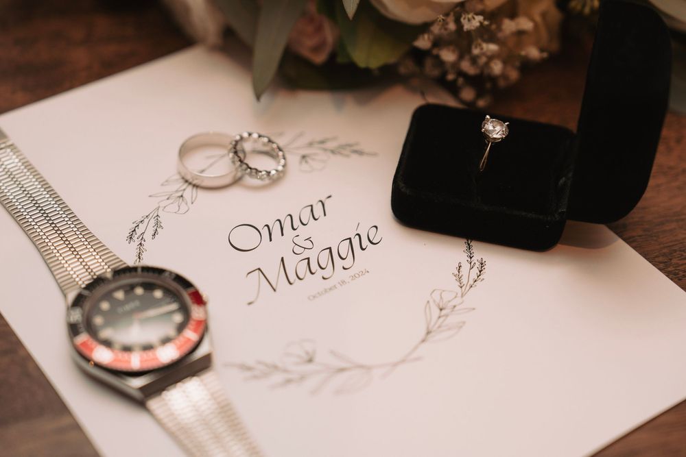 Wedding invitation details and rings photographed on white paper with elegant calligraphy.