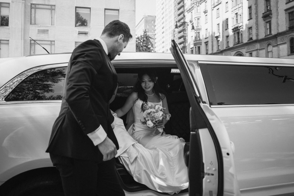A couple enters a white limousine on their wedding day in the city.