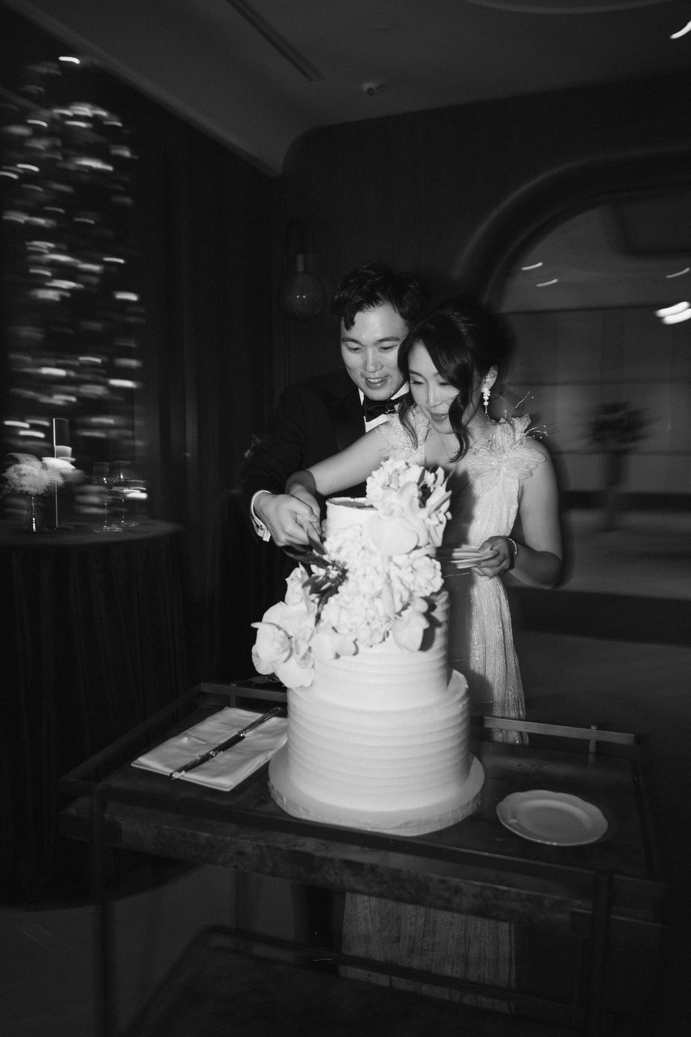 White wedding cake with floral decorations being displayed on a dark table.