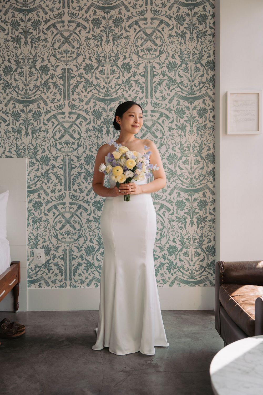 Elegant white wedding dress against blue and white damask wallpaper.