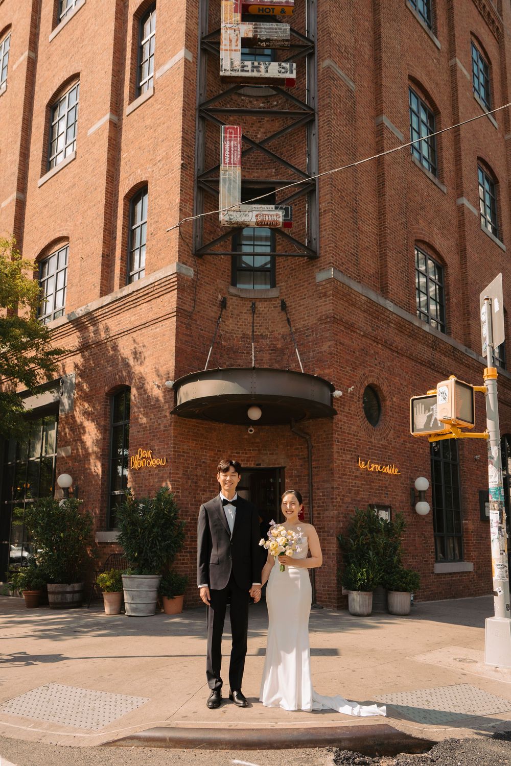 Wedding couple standing outside historic brick building in urban setting.