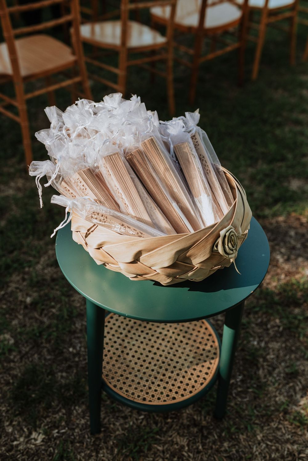 Decorative wedding favors wrapped in white tissue paper arranged on a round teal and gold display stand.