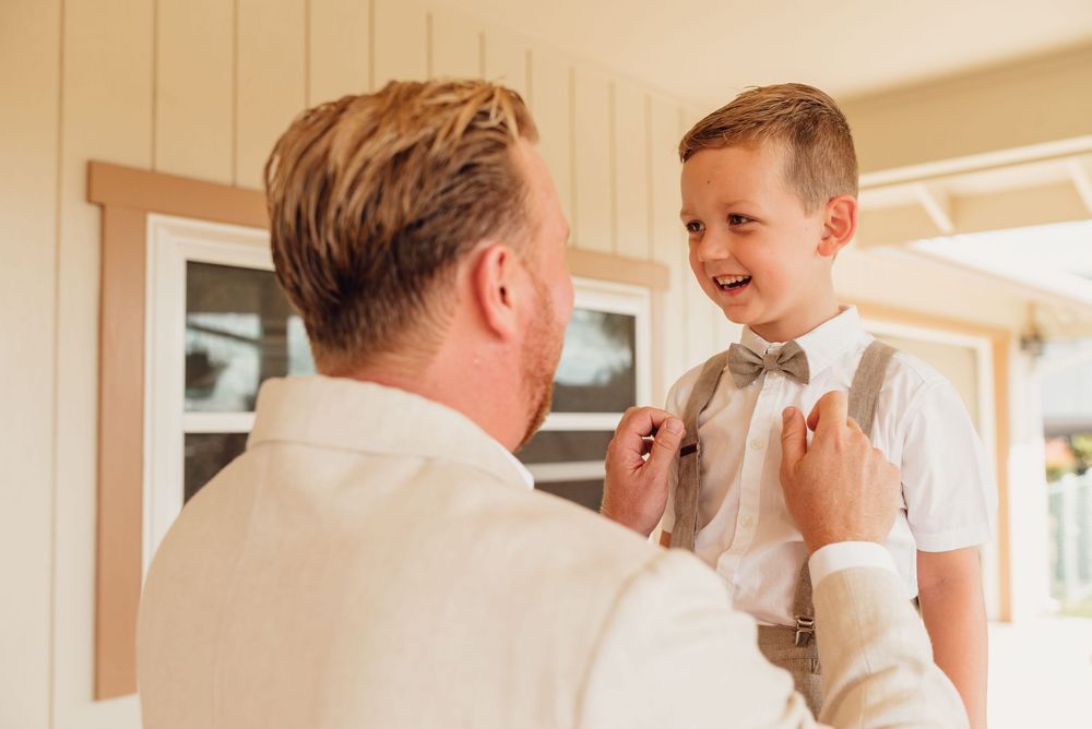 A father and son share a joyful moment together while getting ready in a bright, sunlit room.