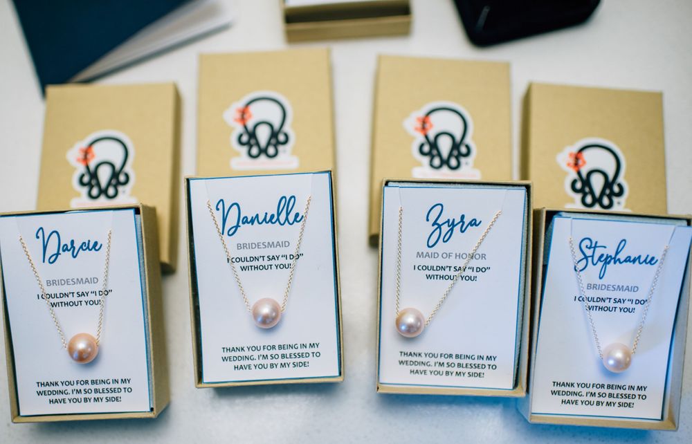 Four personalized wedding favor boxes with pearl accents and calligraphy names.
