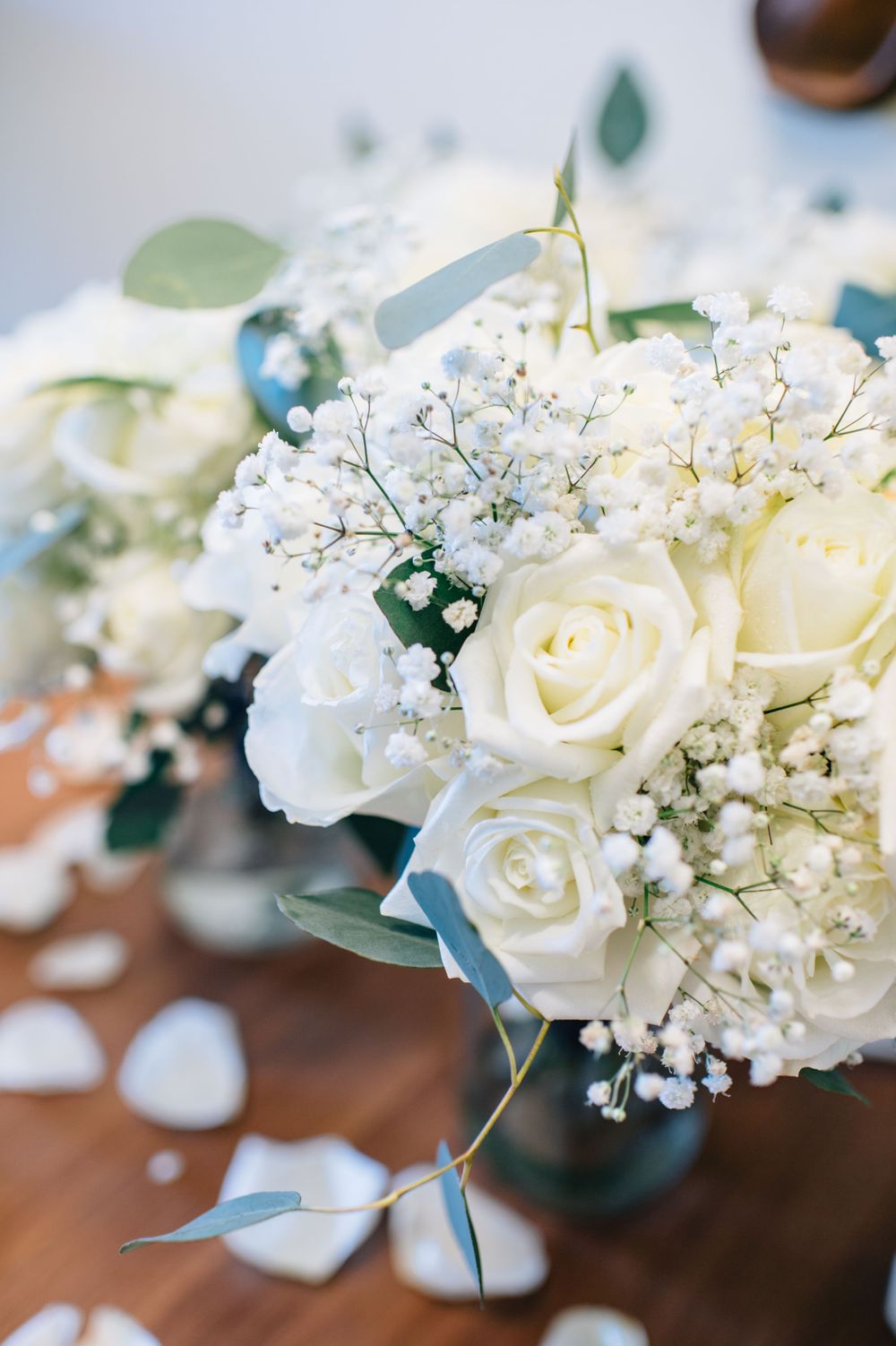 Delicate white rose and baby's breath wedding bouquet with eucalyptus leaves.