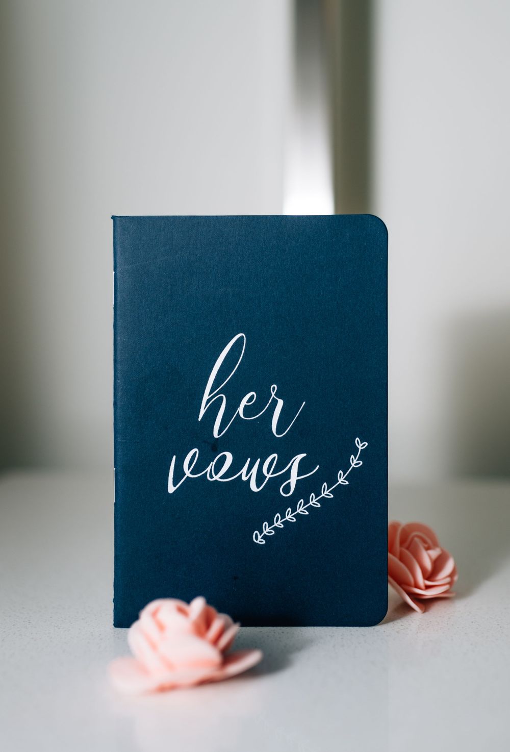 Navy blue wedding stationery cards with elegant calligraphy and pink floral accents.