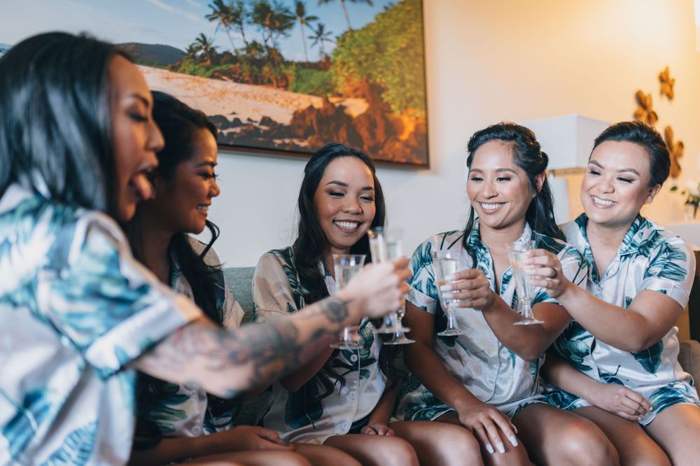Wedding party getting ready together in matching floral robes with joyful expressions.