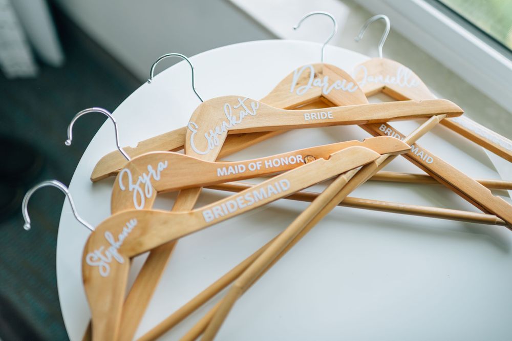 Wooden hangers with white text arranged neatly for wedding attire.