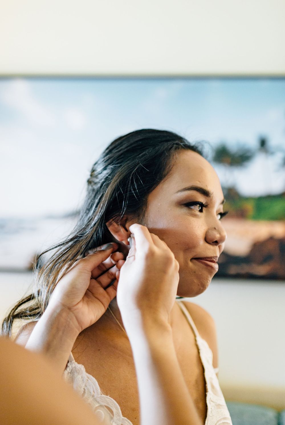 Bride having final touches of makeup applied with beach scenery in background.