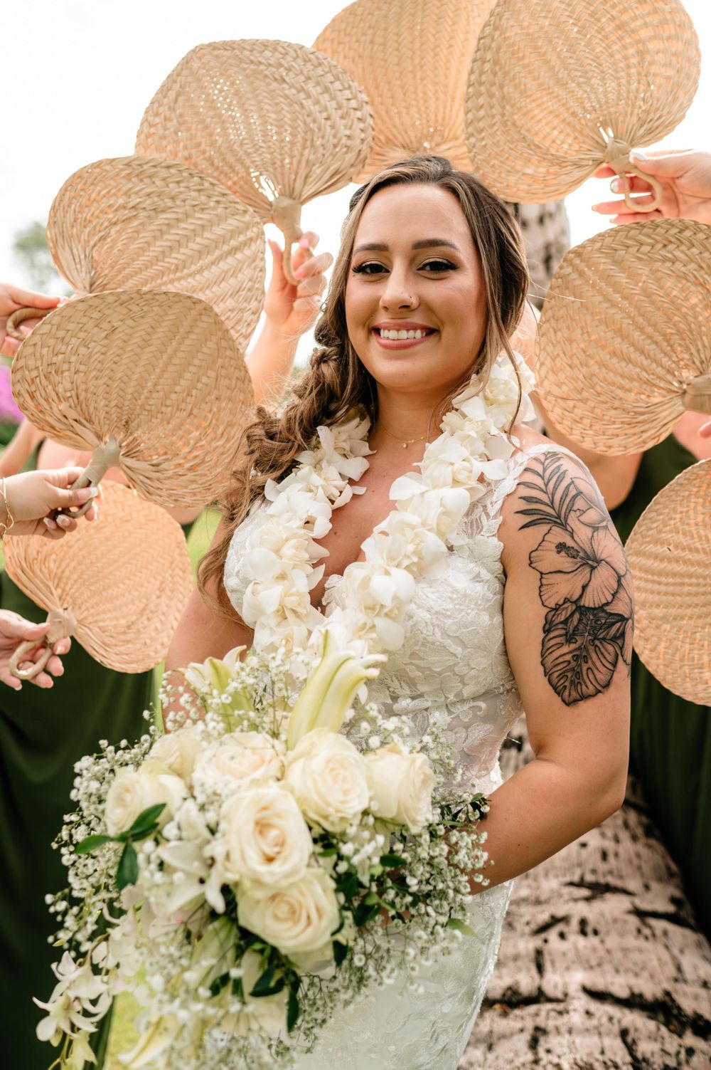 Bridal party holding decorative palm leaf fans with white floral bouquets.