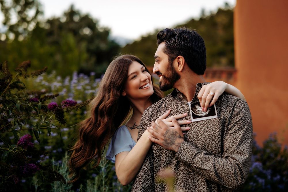 Happy couple embracing and laughing together in colorful garden with purple flowers.