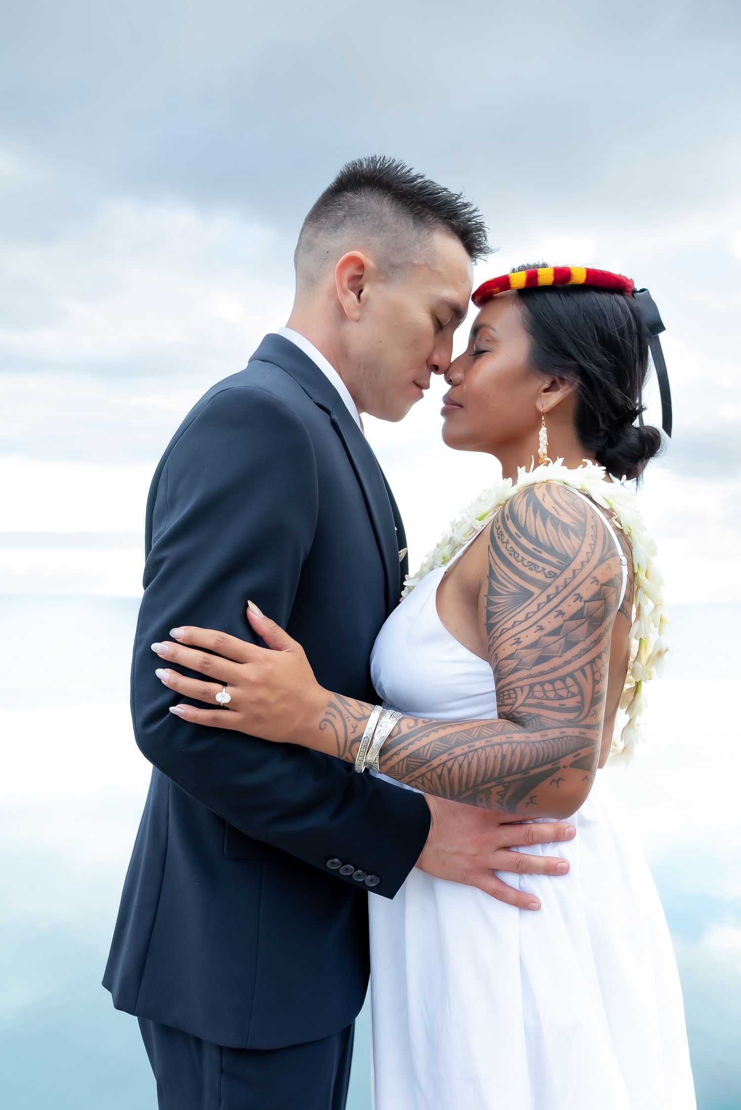 A romantic wedding couple embraces and kisses against a cloudy sky backdrop in a series of intimate photos.