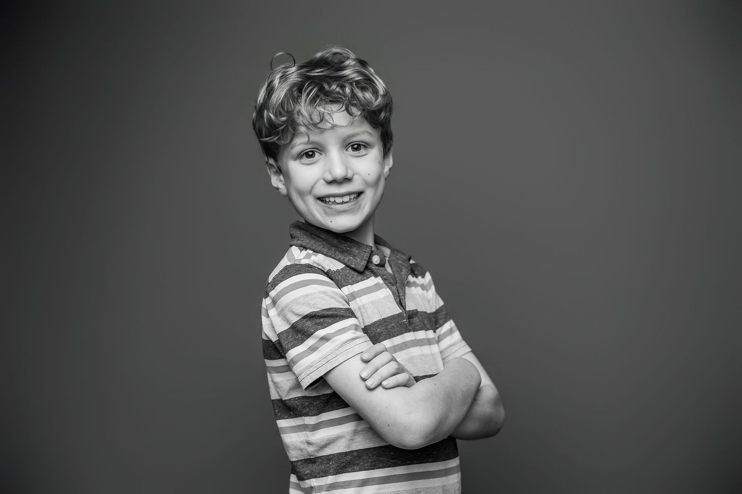 Black and white photo series showing a young child in striped shirt making different playful expressions and poses.