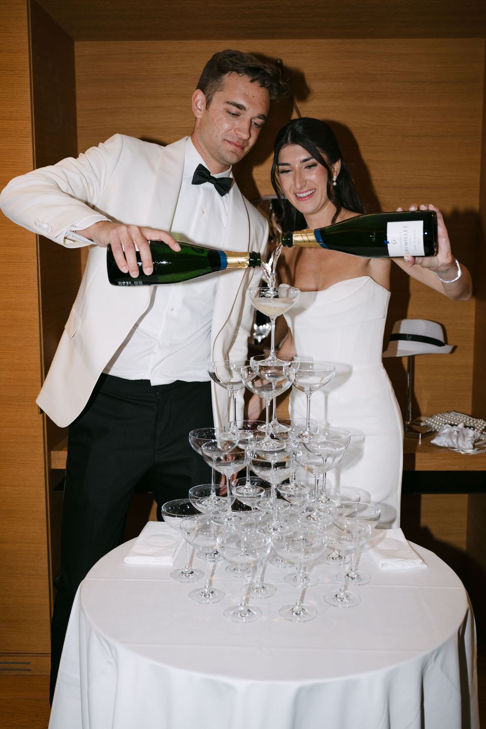 Servers pour champagne into a tower of elegant crystal glasses at an upscale event.