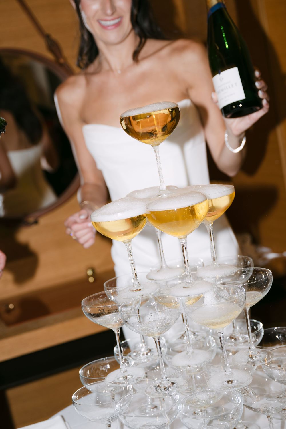 A champagne tower being set up at an elegant event with stacked coupe glasses ready to be filled.