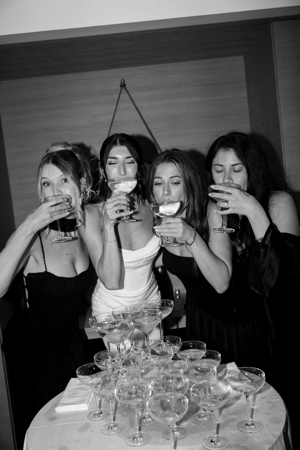 A black and white photo of people drinking from wine glasses at a party gathering.