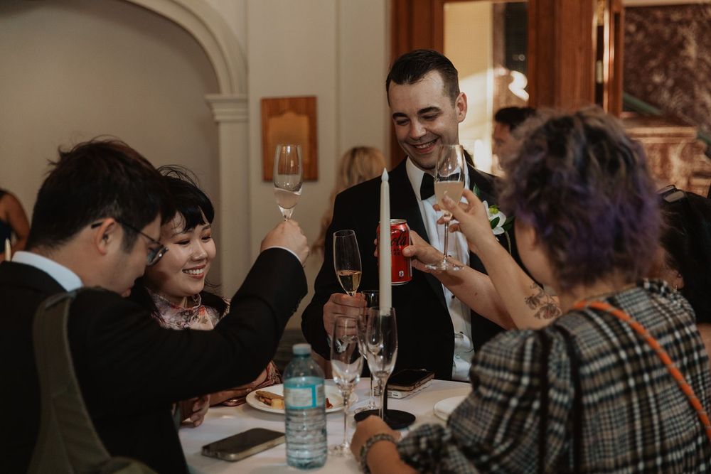Guests raising champagne glasses in a toast at an elegant wedding reception dinner.