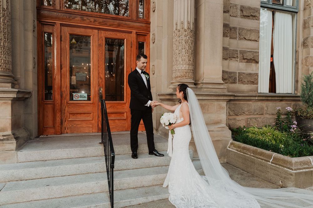 Bride and groom sharing a first look moment outside an elegant stone building entrance.