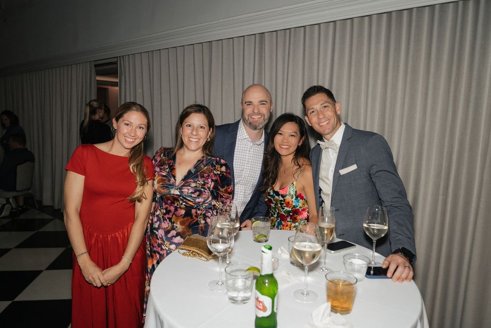 Group of people enjoying dinner together at a formal table setting with wine glasses and drinks.