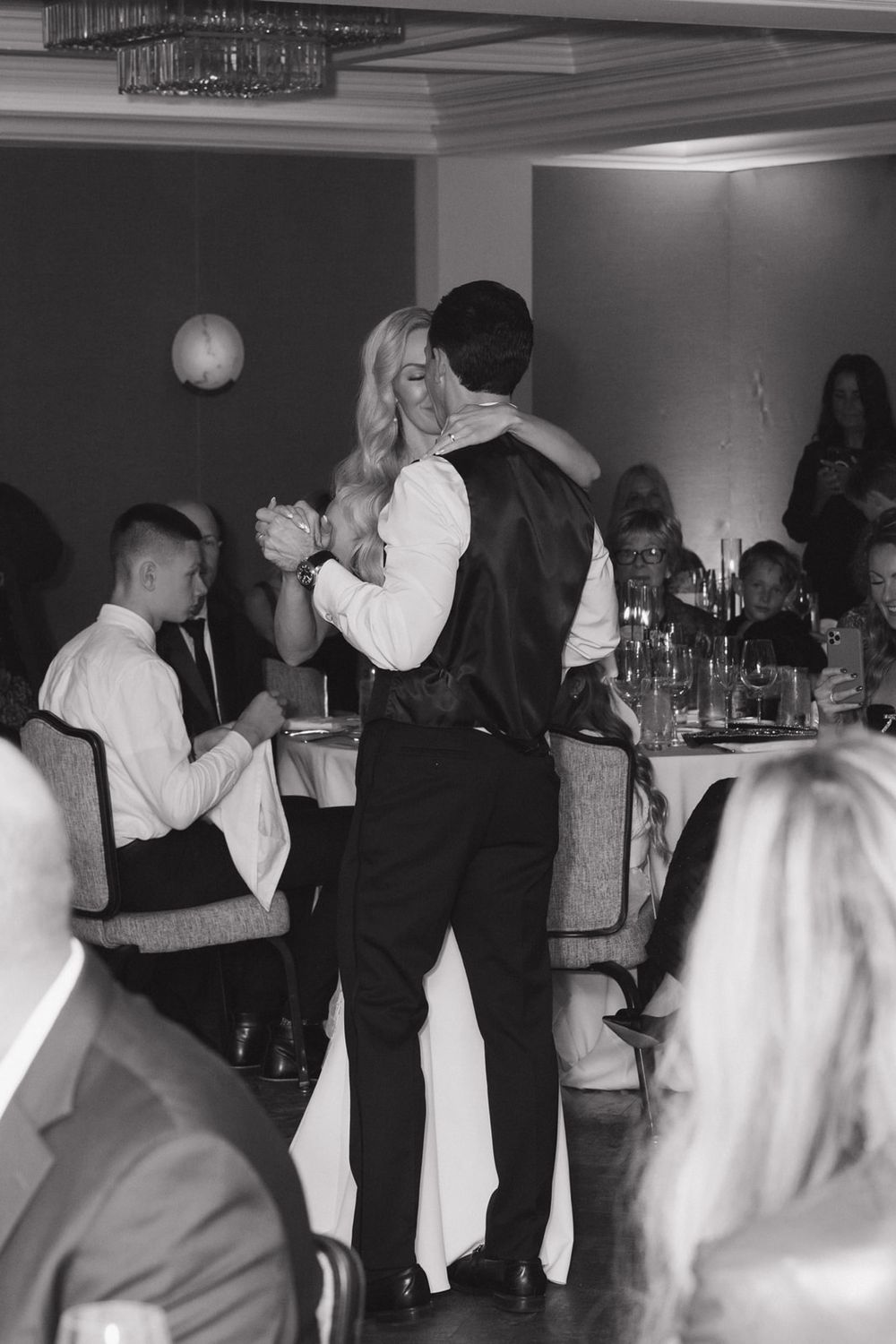 Black and white photo showing couples dancing together at a wedding reception on a dance floor.