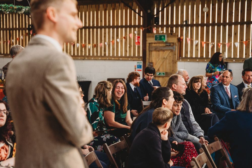 Guests seated in rows at an indoor ceremony venue with natural lighting.