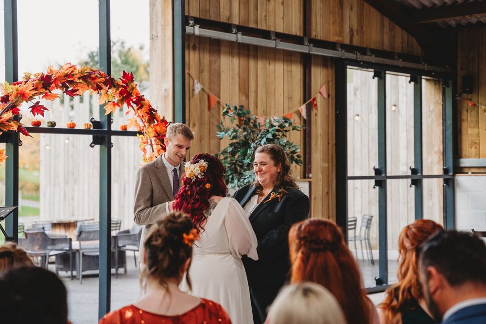 Rustic barn wedding venue decorated with autumn-colored floral arches.