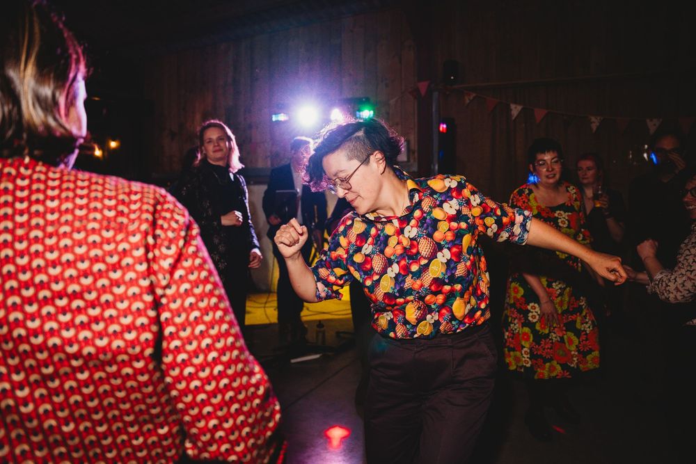 Dark reception venue with colorful lighting and guests dancing in festive attire.
