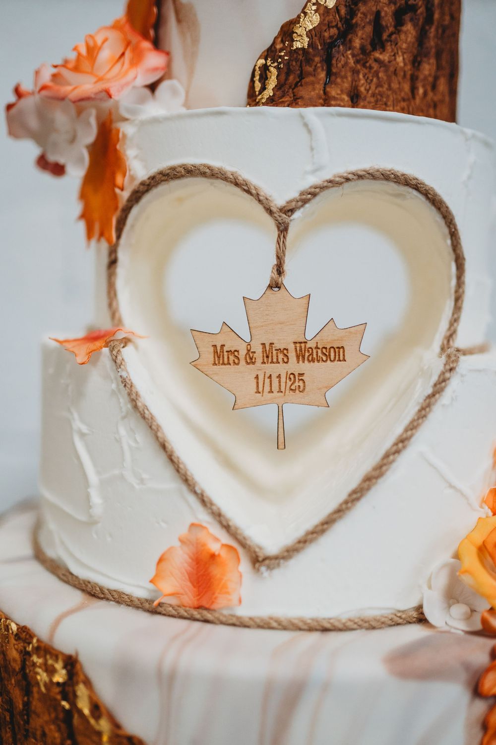 White wedding cake plate decorated with rope heart design and personalized wooden name tag.