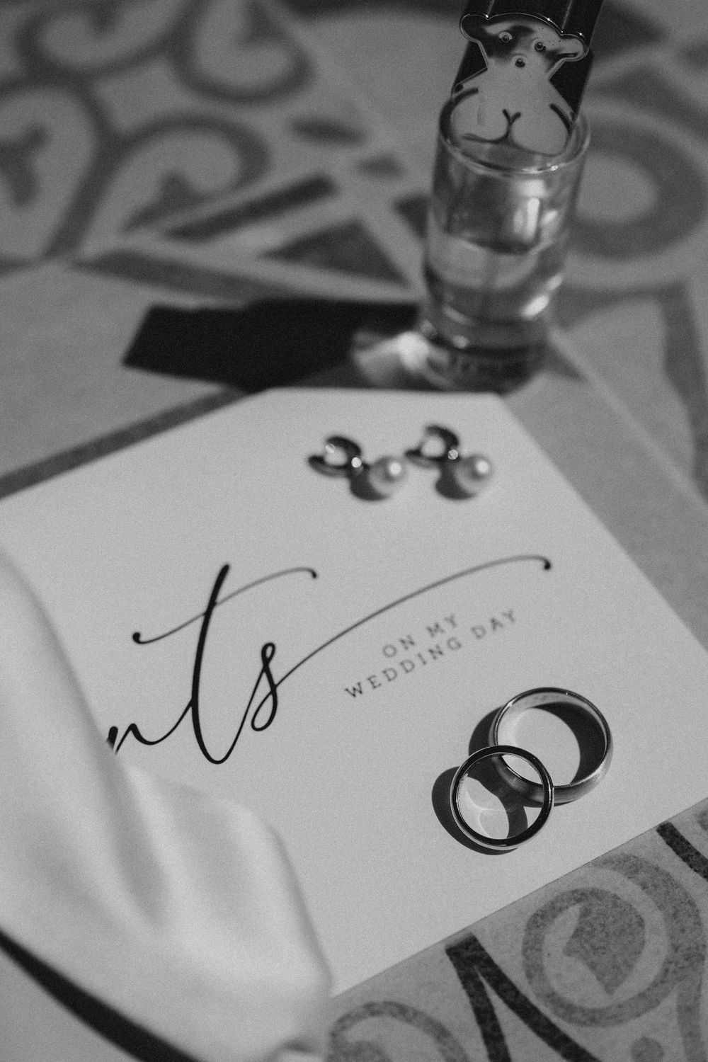 Black and white close-up shots of elegant wedding stationery with calligraphy details and decorative patterns.