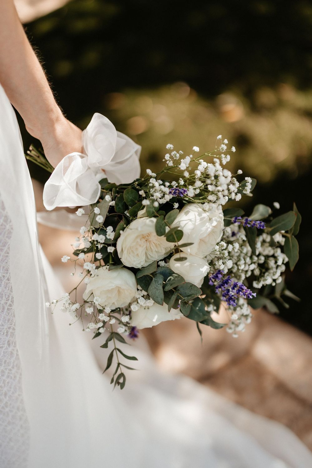 Delicate white floral bouquet with baby's breath and greenery arranged in an elegant wedding style.