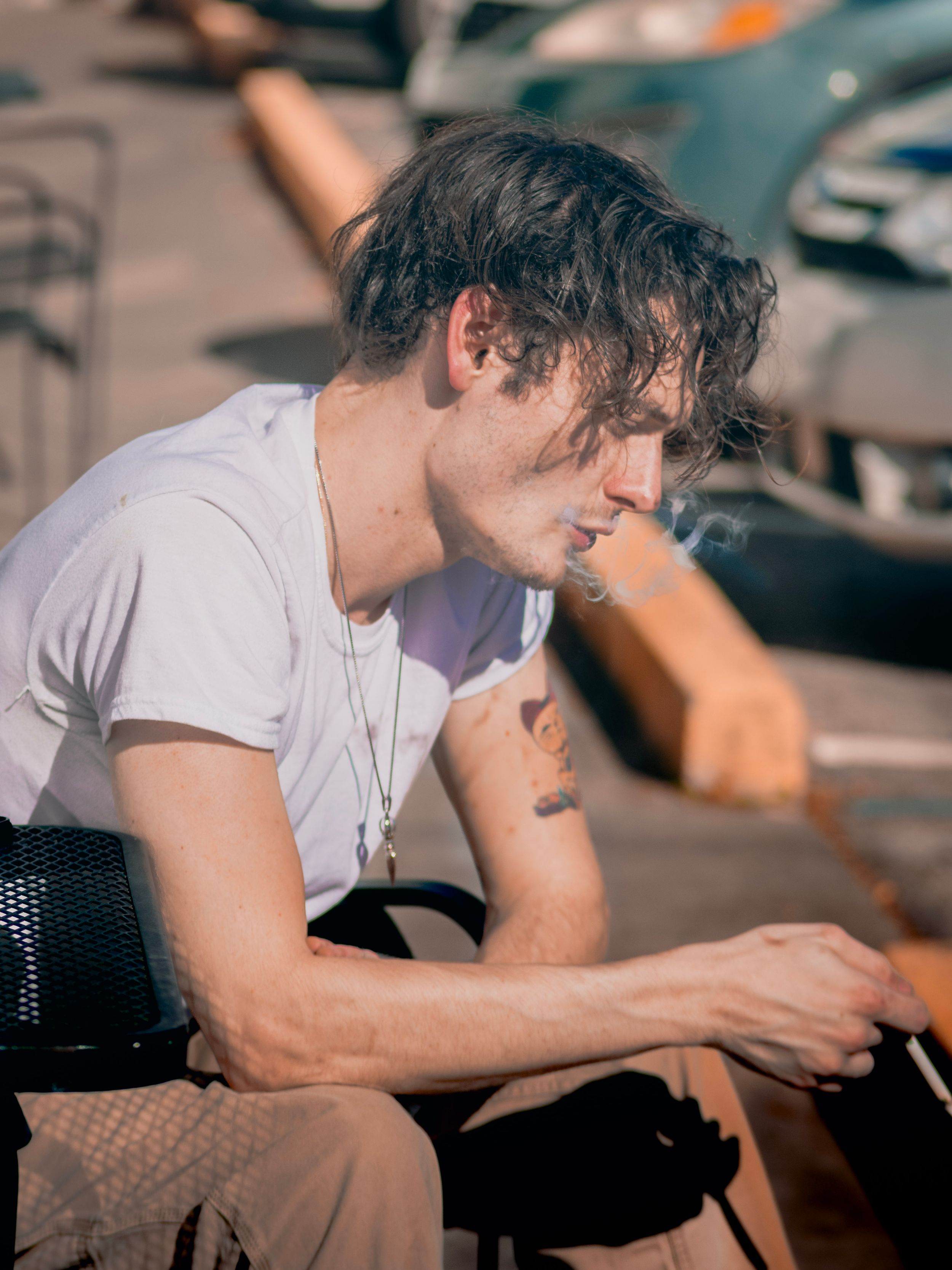 Person in white t-shirt sitting outdoors in casual pose during daytime.