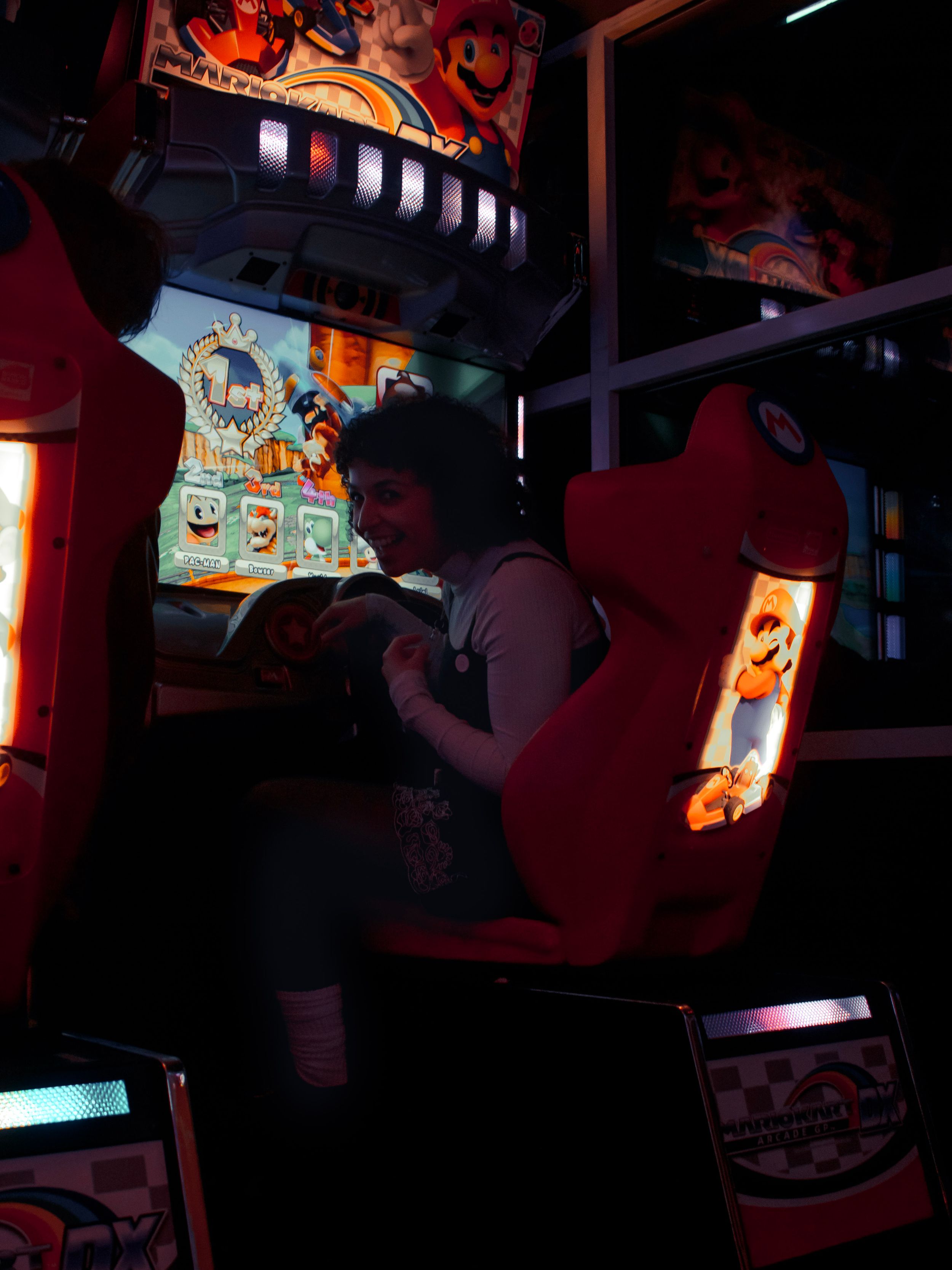 Arcade game cabinet glows with colorful lights in dark gaming room.