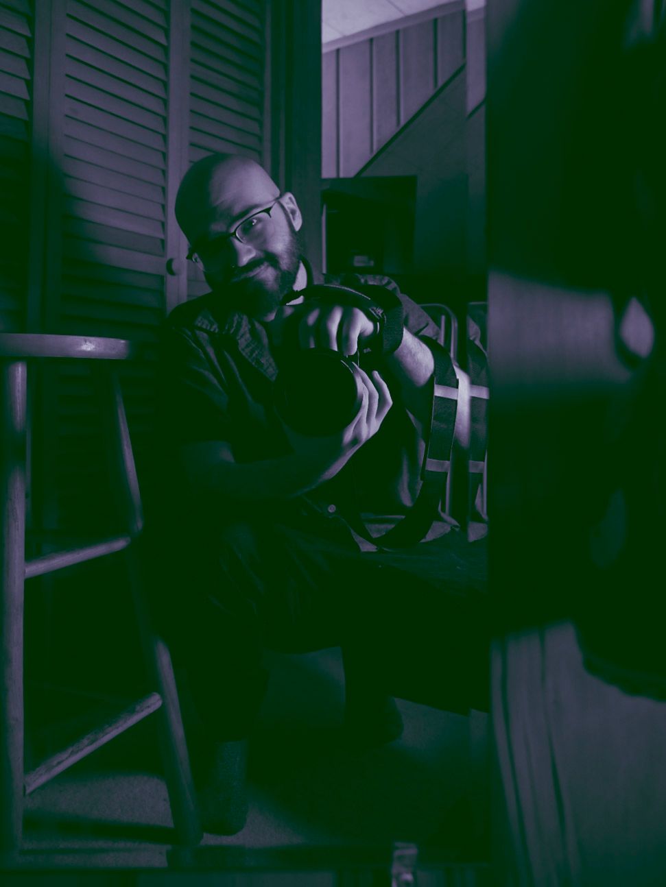 Dimly lit interior scene with blue tinted lighting and venetian blinds casting shadows.