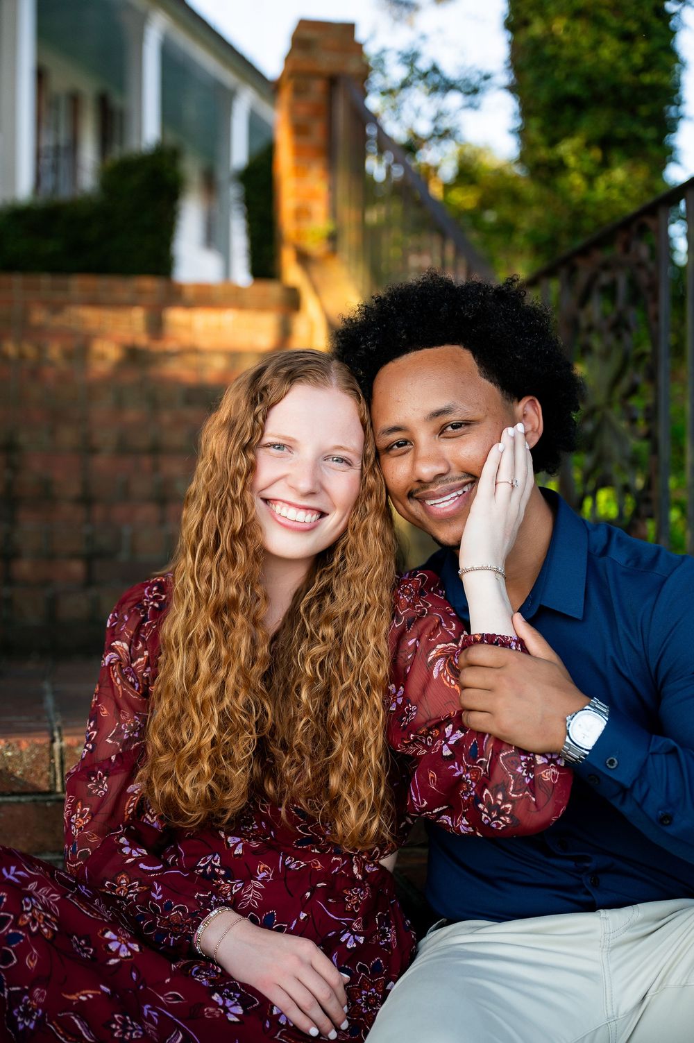 A romantic couple laughs together while sitting outdoors during golden hour.