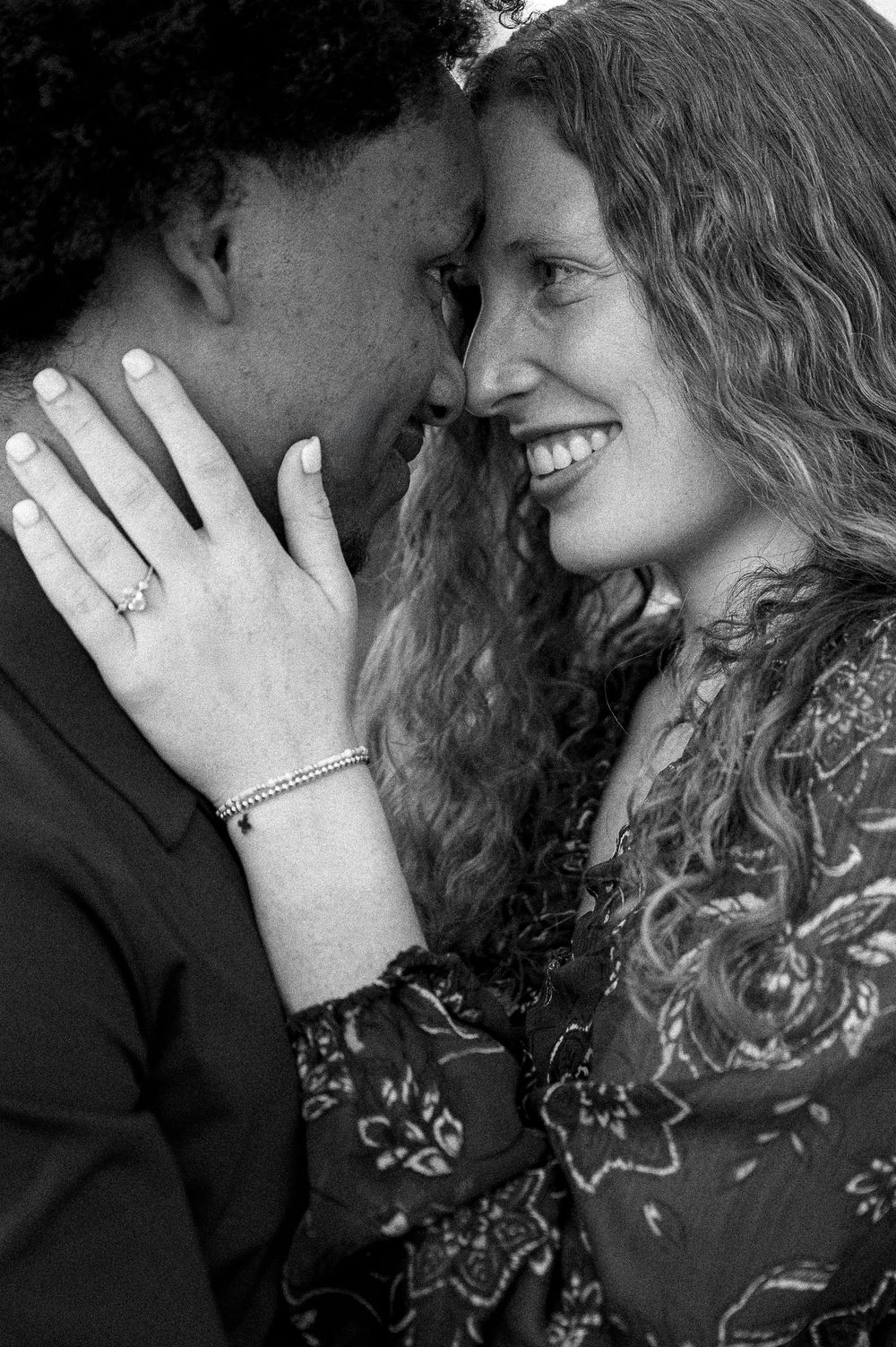 An intimate black and white portrait of a couple sharing a tender moment.