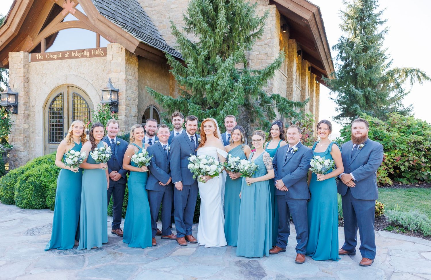 Wedding party in blue and navy attire poses together outdoors for formal group photos with Janie Loftin Photography at Big Cedar Lodge.