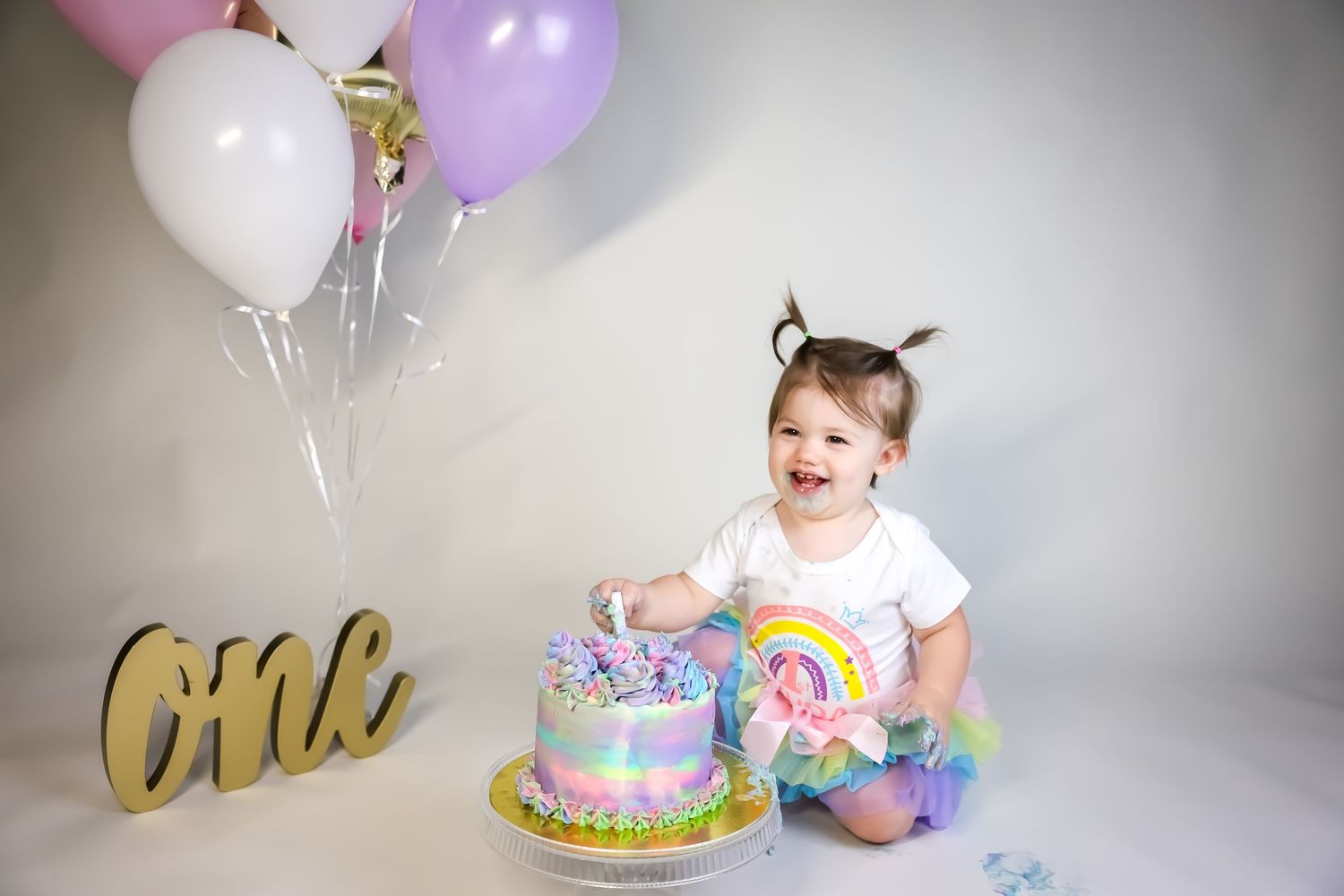 Colorful birthday scene with pastel balloons, cake, and rainbow tutu decorations.