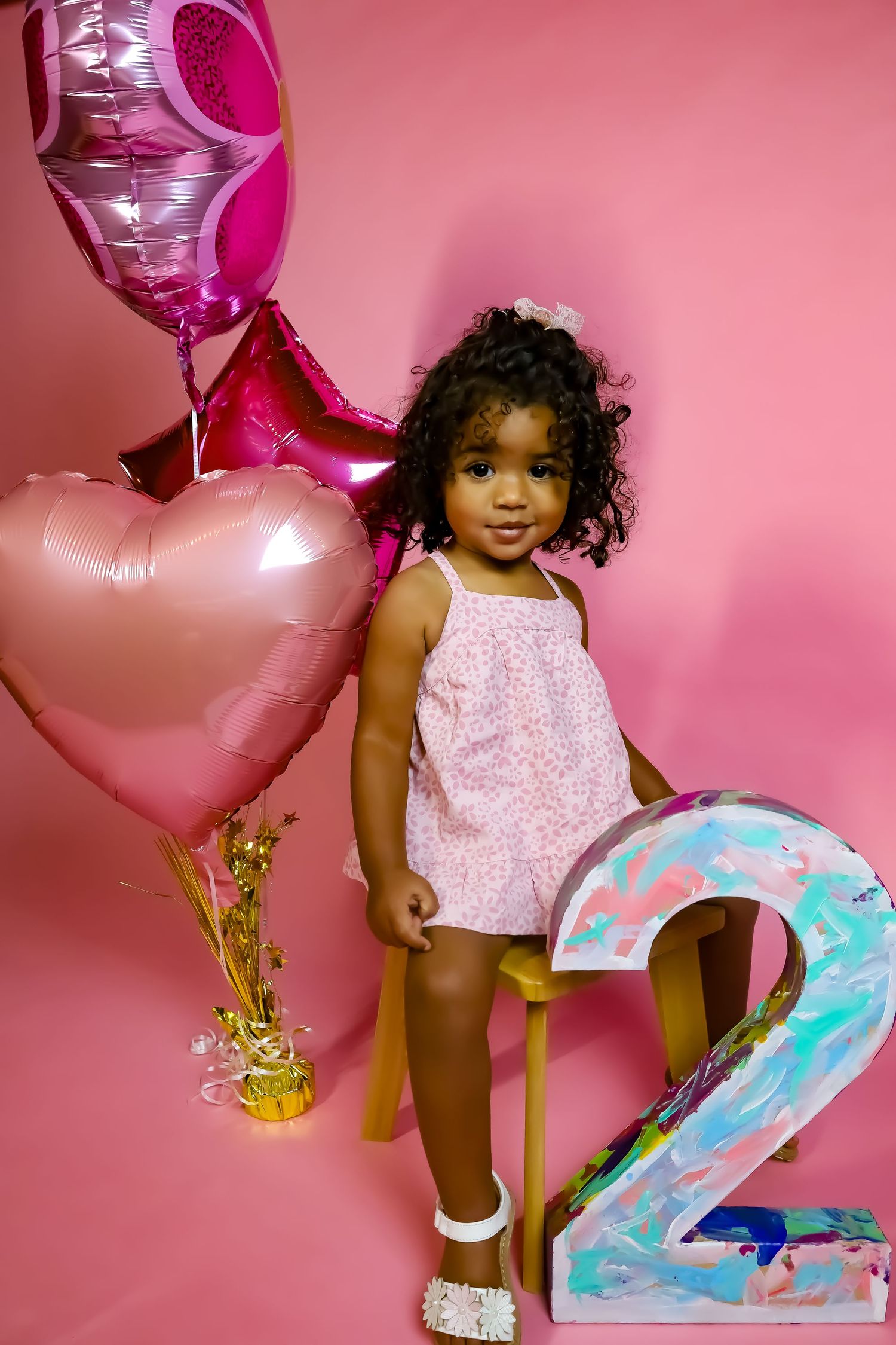 Birthday photoshoot with number 2 balloon and pink background.