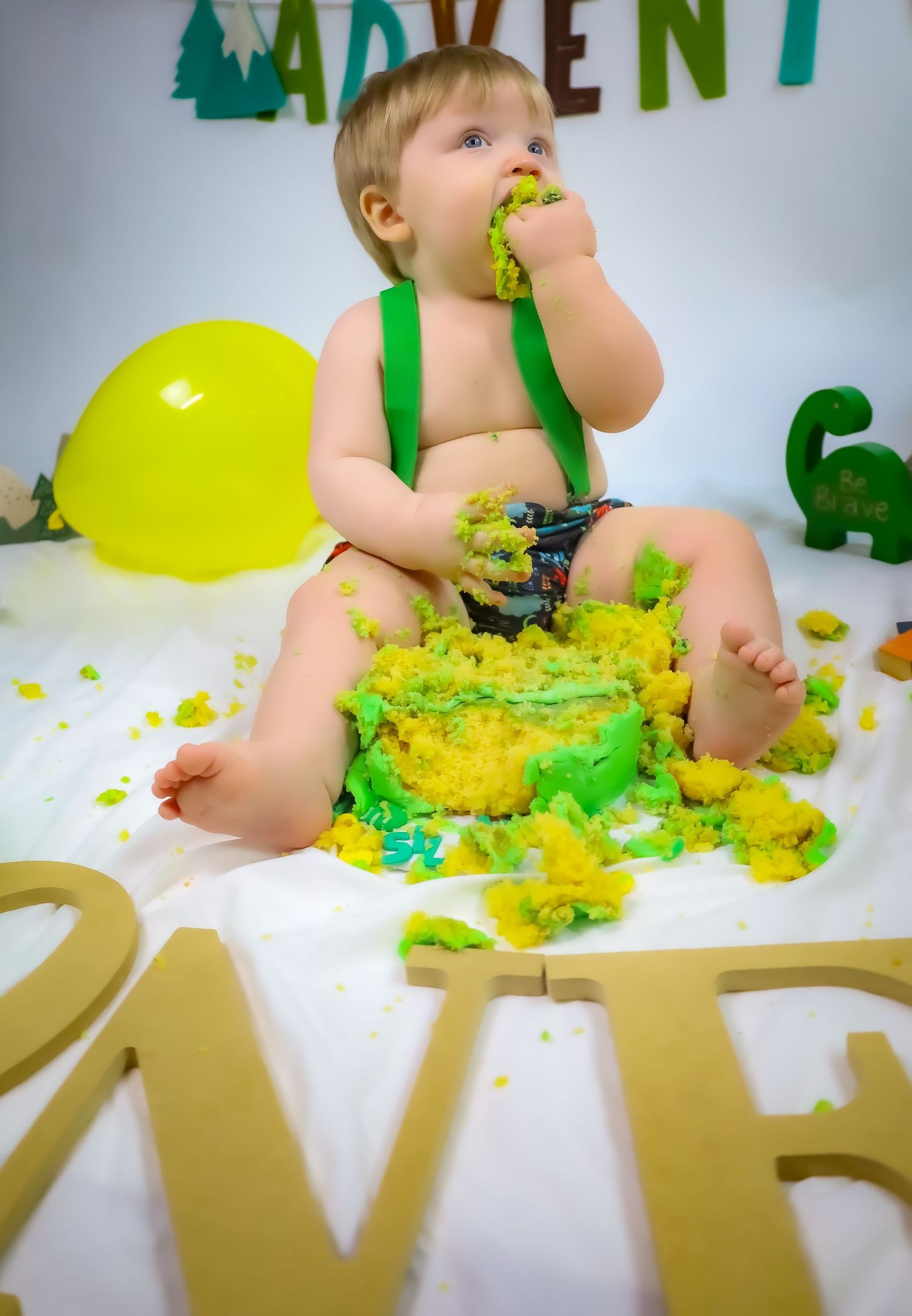 Messy cake smash photo session with green frosting and gold letters.