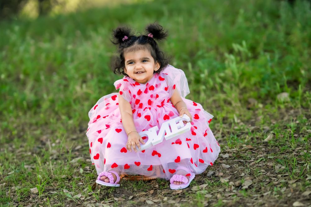 Sweet pink and white heart patterned dress with puffed sleeves worn outdoors on green grass.