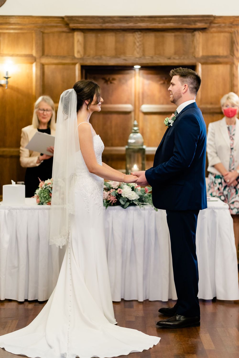 Elegant wedding reception setup with white tablecloths and couples dancing in a wood-paneled ballroom.