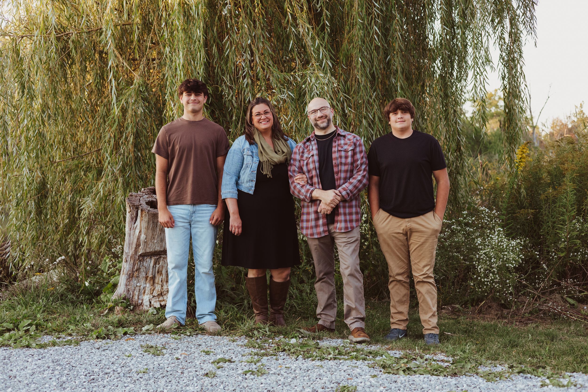 A group of people standing together under a weeping willow tree for a casual outdoor portrait.