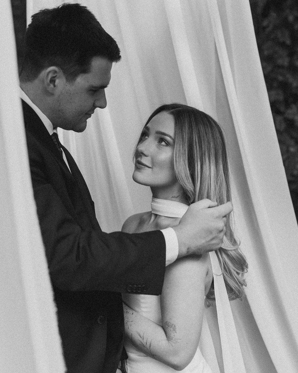 Black and white romantic photo sequence showing a couple in formal wear embracing against white curtains.