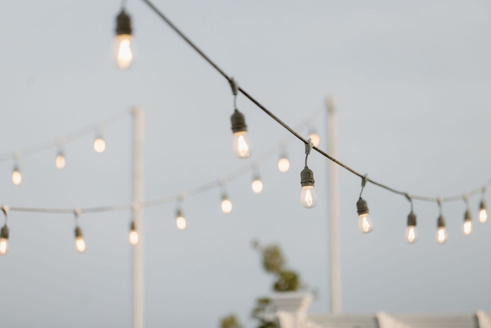 String lights hang between poles creating an outdoor ambiance against a cloudy sky at dusk.