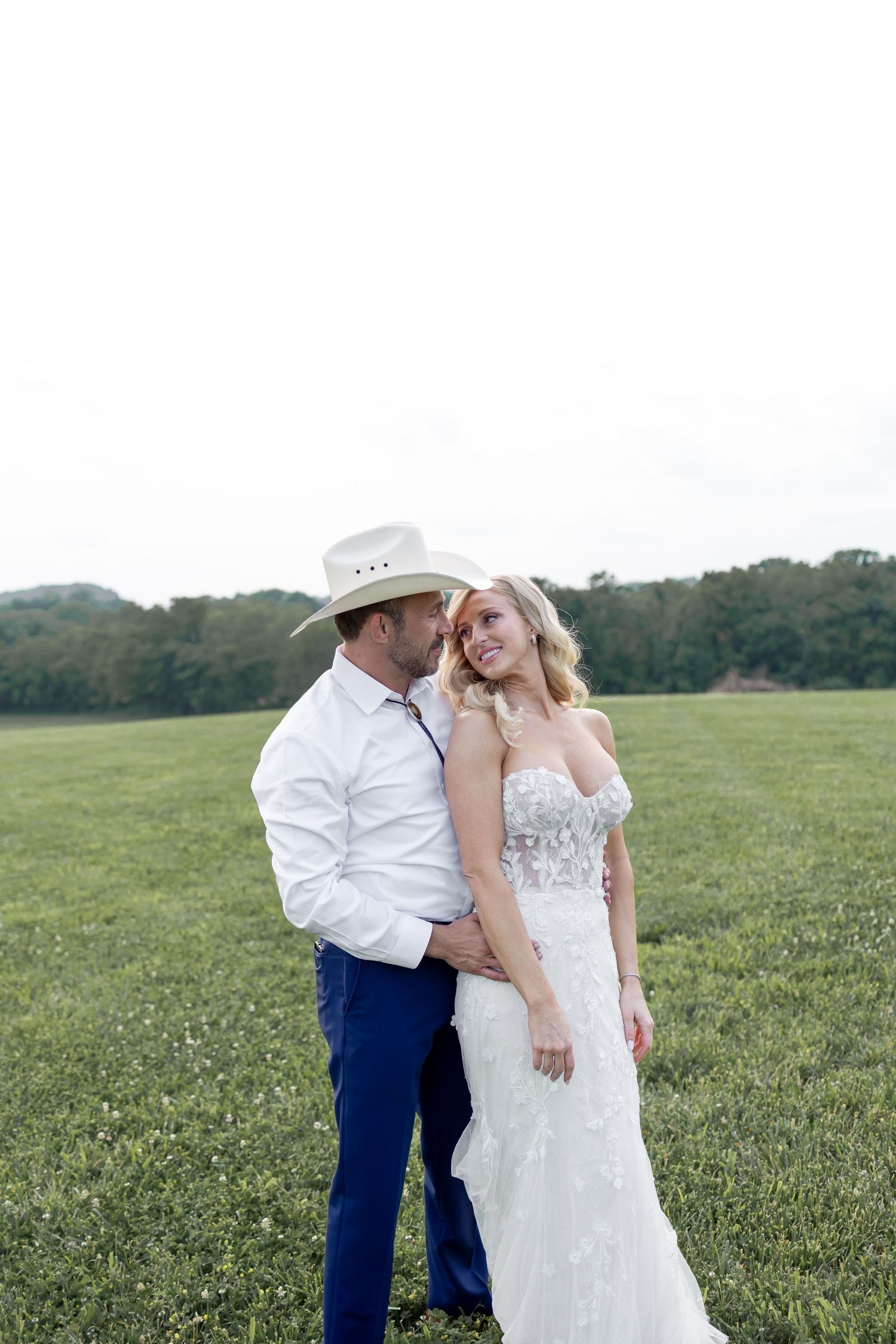 A romantic couple shares tender moments in a lush green field during their wedding photo session.
