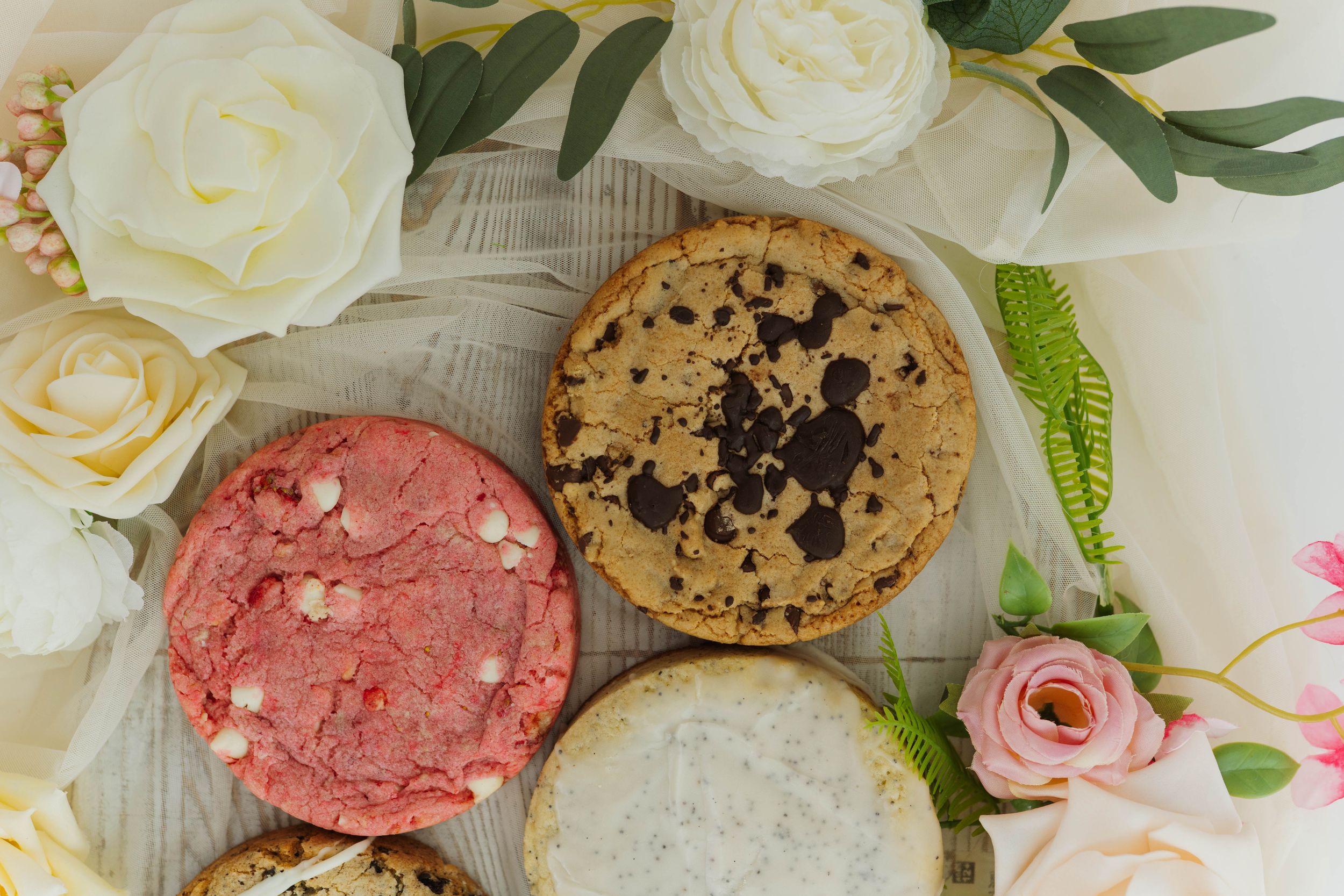 Artisanal cookies and fresh roses arranged on a rustic wooden backdrop.